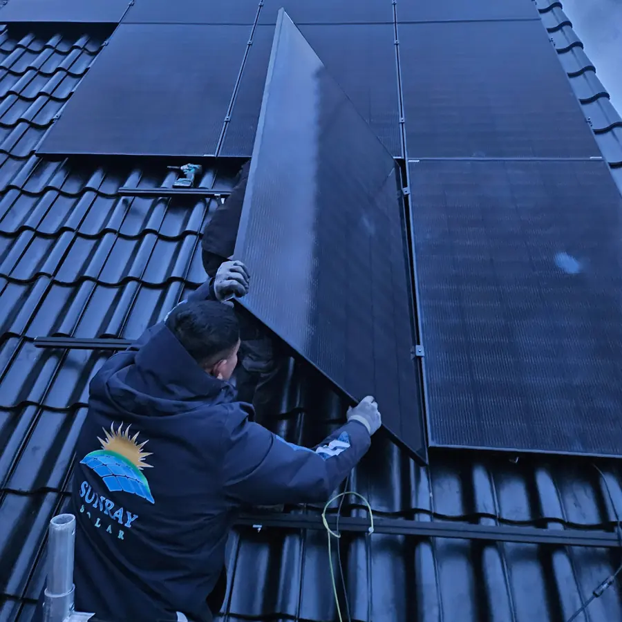 Installateur in een Sunray Solar-jas plaatst een zonnepaneel op een dak